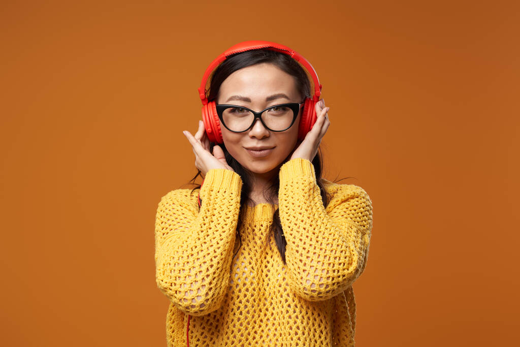 戴眼镜的布鲁内特妇女正在用红色耳机听音乐图片