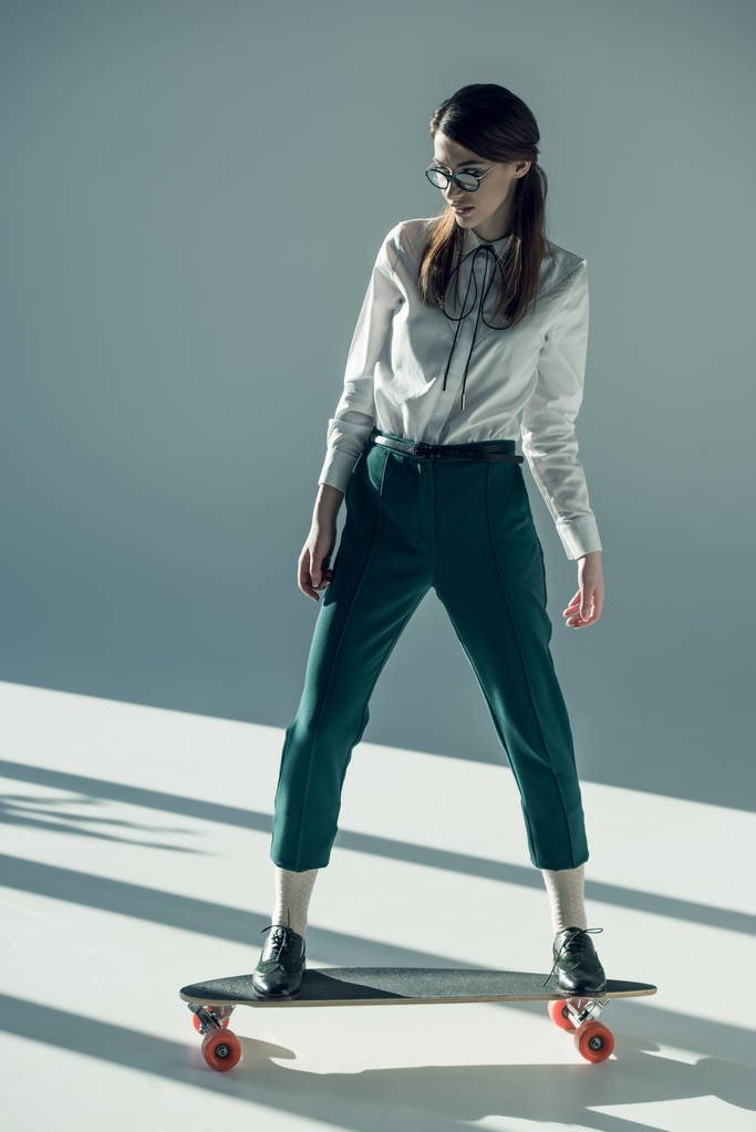 hipster woman standing on skateboard